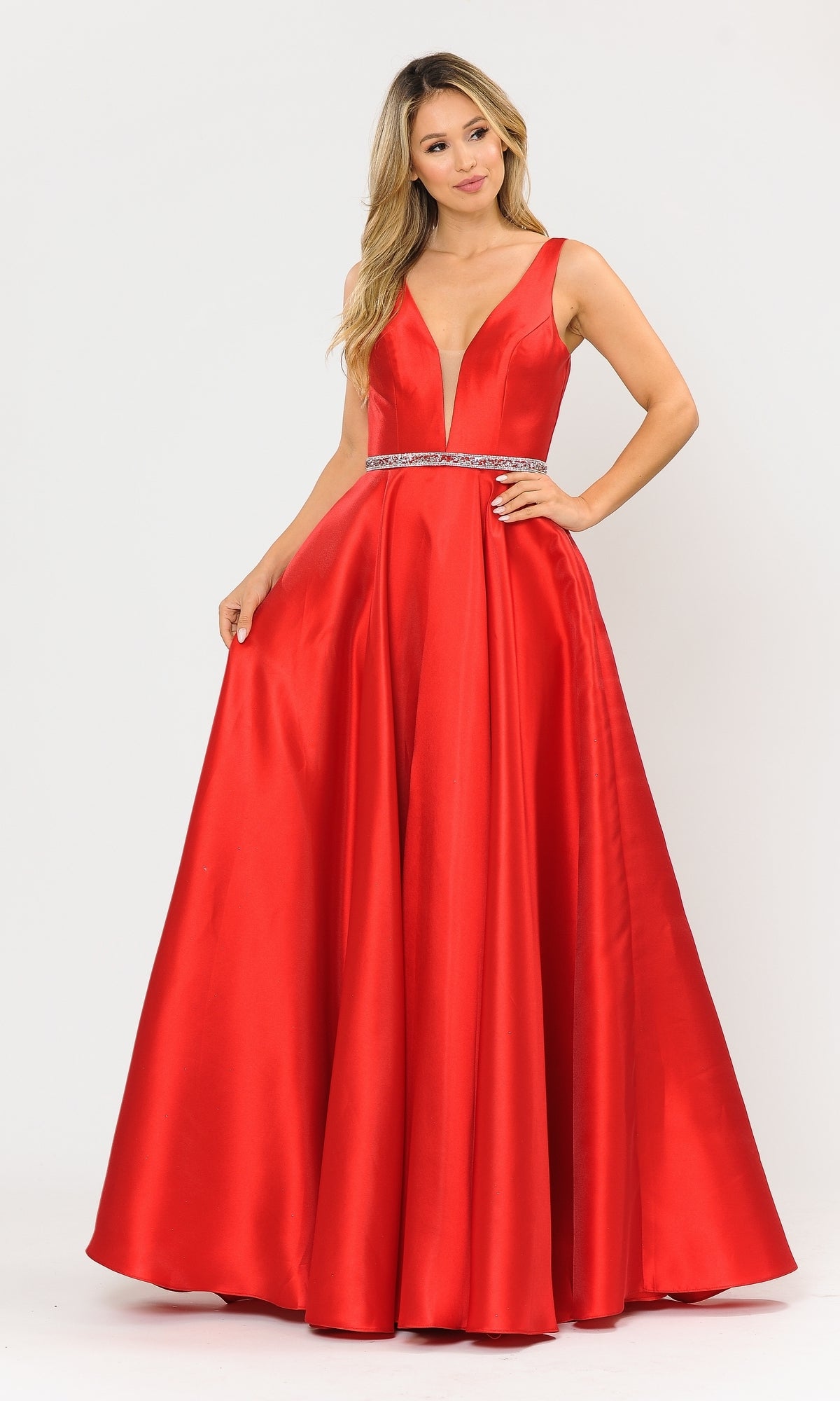A woman stands against a plain white background wearing the Deep V-Neck Long Mikado A-Line Prom Dress 8682, a sleeveless, floor-length gown with a deep V-neckline and rhinestone belt.